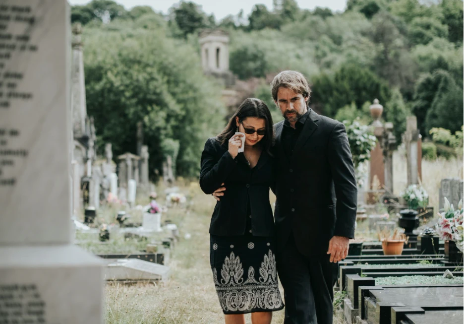 A family walking together through a cemetery after a funeral